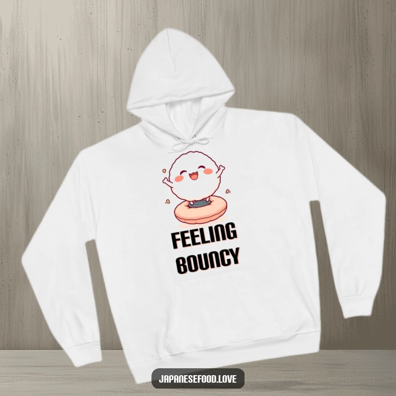 Funny hoodie showcasing a smiling rice ball character bouncing with delight on a springy cushion, offering cozy and cheerful vibes.