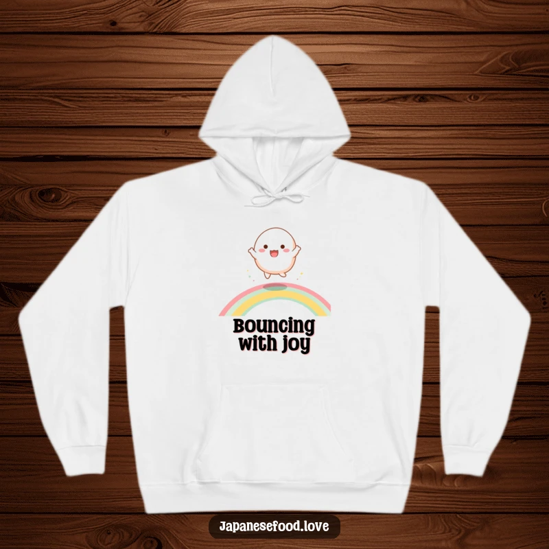 Funny hoodie depicting a happy mochi character joyfully bouncing and dancing on a vibrant, shimmering rainbow.