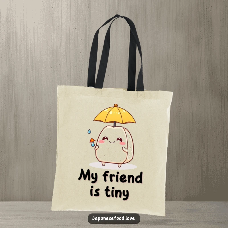 Funny grinning onigiri offering a tiny umbrella to a small raindrop buddy, printed on a reusable tote bag.